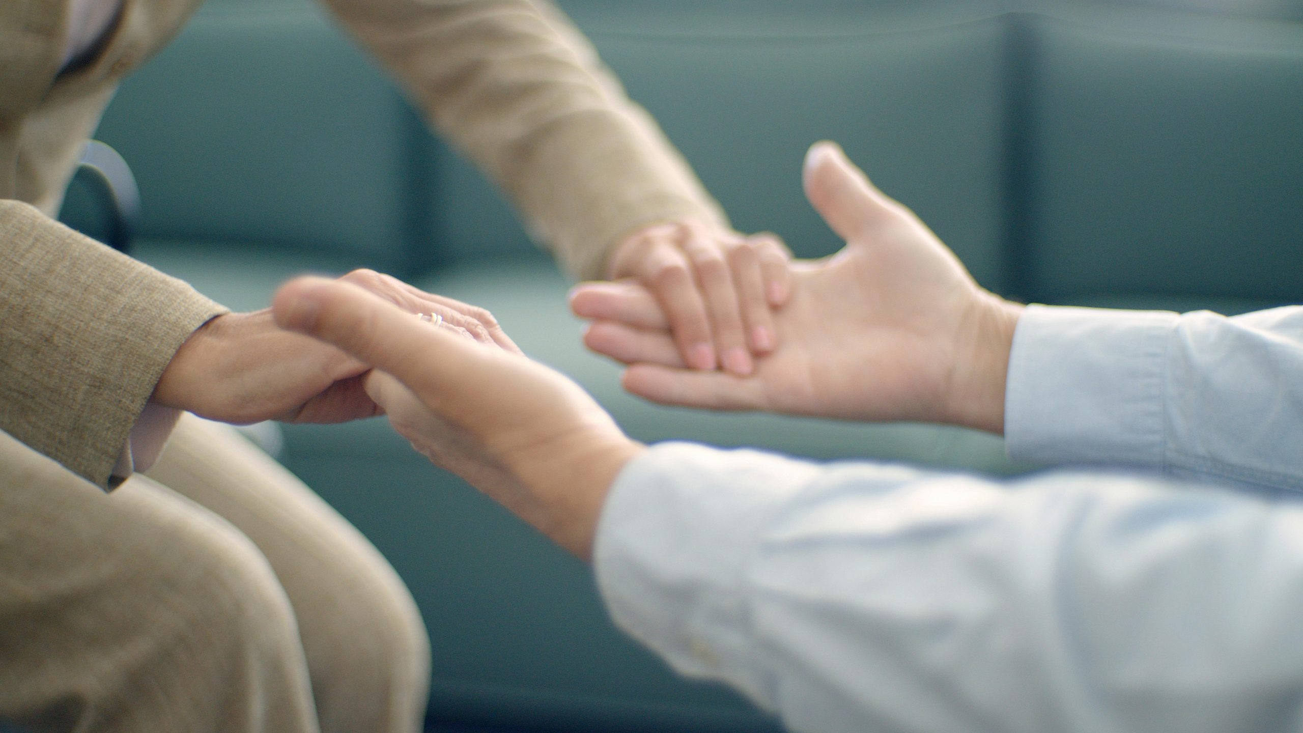 Close-up of two people holding hands, symbolizing support and compassion in a peaceful setting.